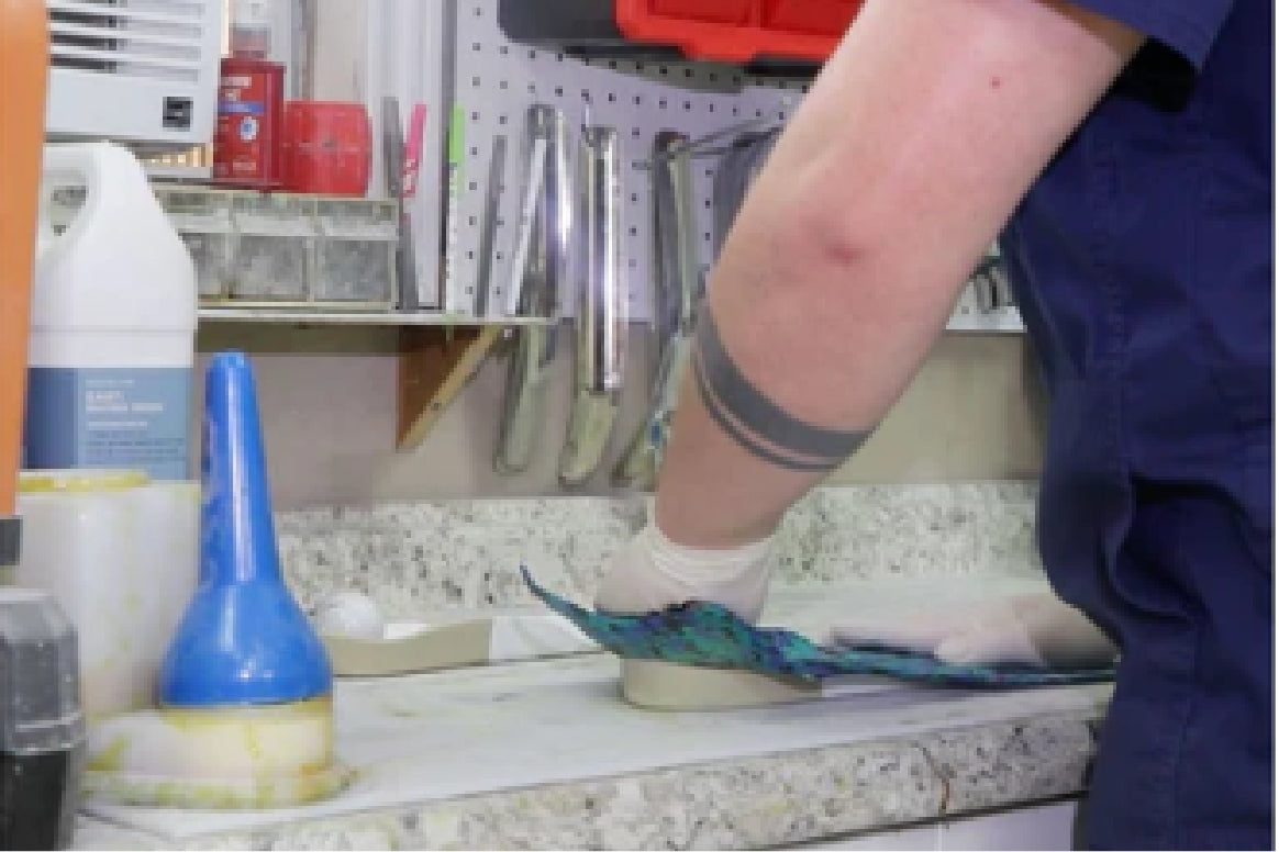 Technician at Texas Foot Orthotics crafting a fully custom orthotic by hand in a workshop, shaping and molding materials from scratch to create a unique, patient-specific fit rather than using prefabricated templates