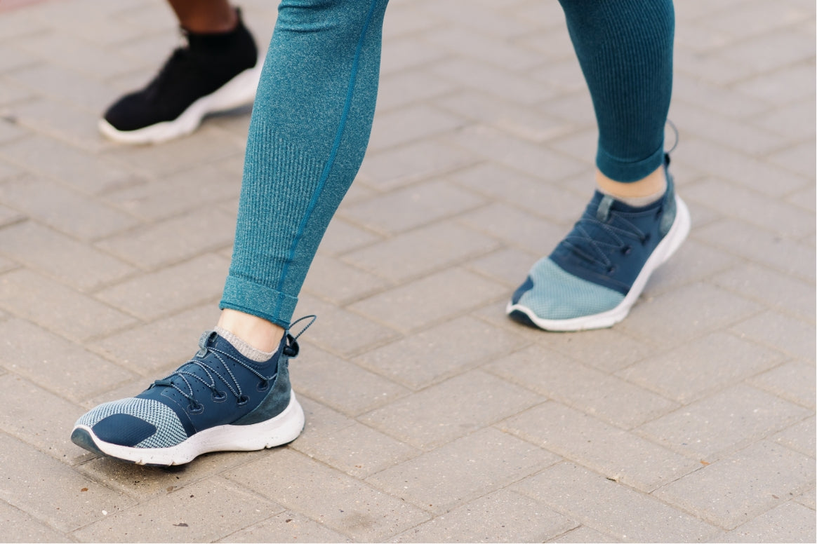 Close-up of a person walking in athletic shoes on a paved surface, representing the comfort and immediate support of Texas Foot Orthotics with zero break-in time